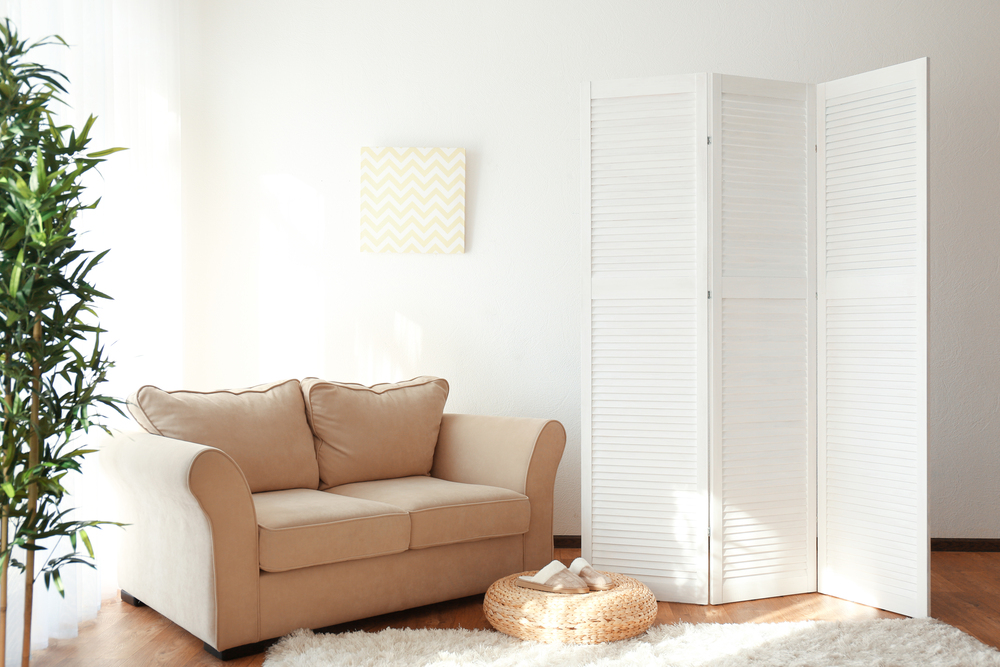 Espacio moderno y minimalista con muebles auxiliares como un biombo decorativo y un sofá, ideales para añadir confort y estilo al hogar.